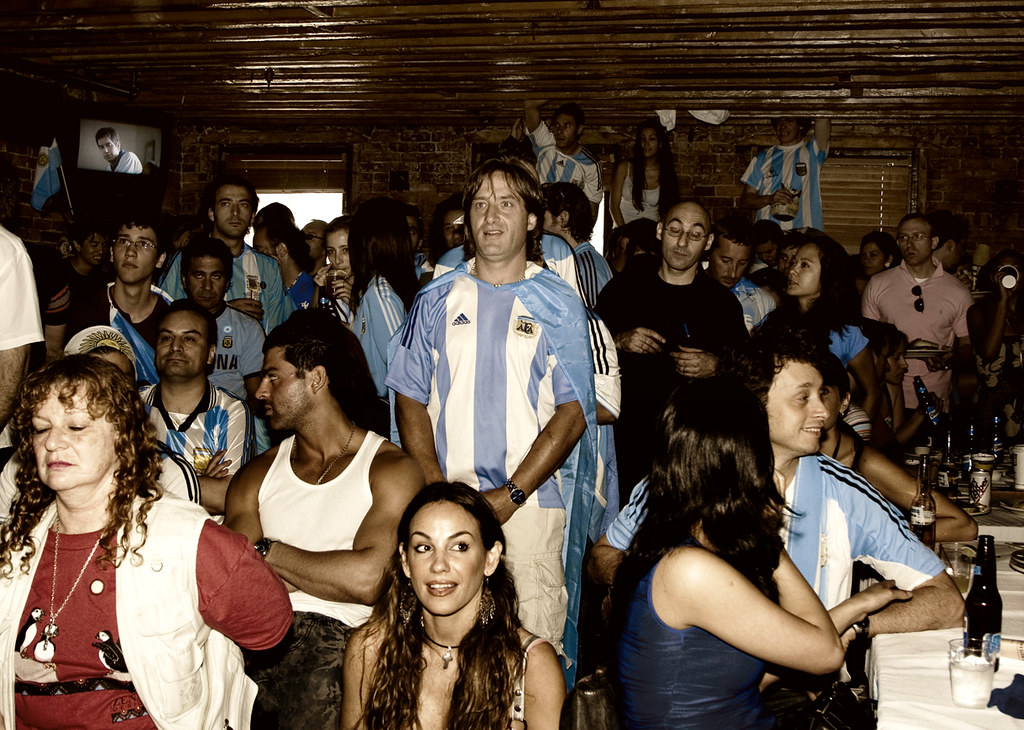 A packed bar of fans watching a match on a small television